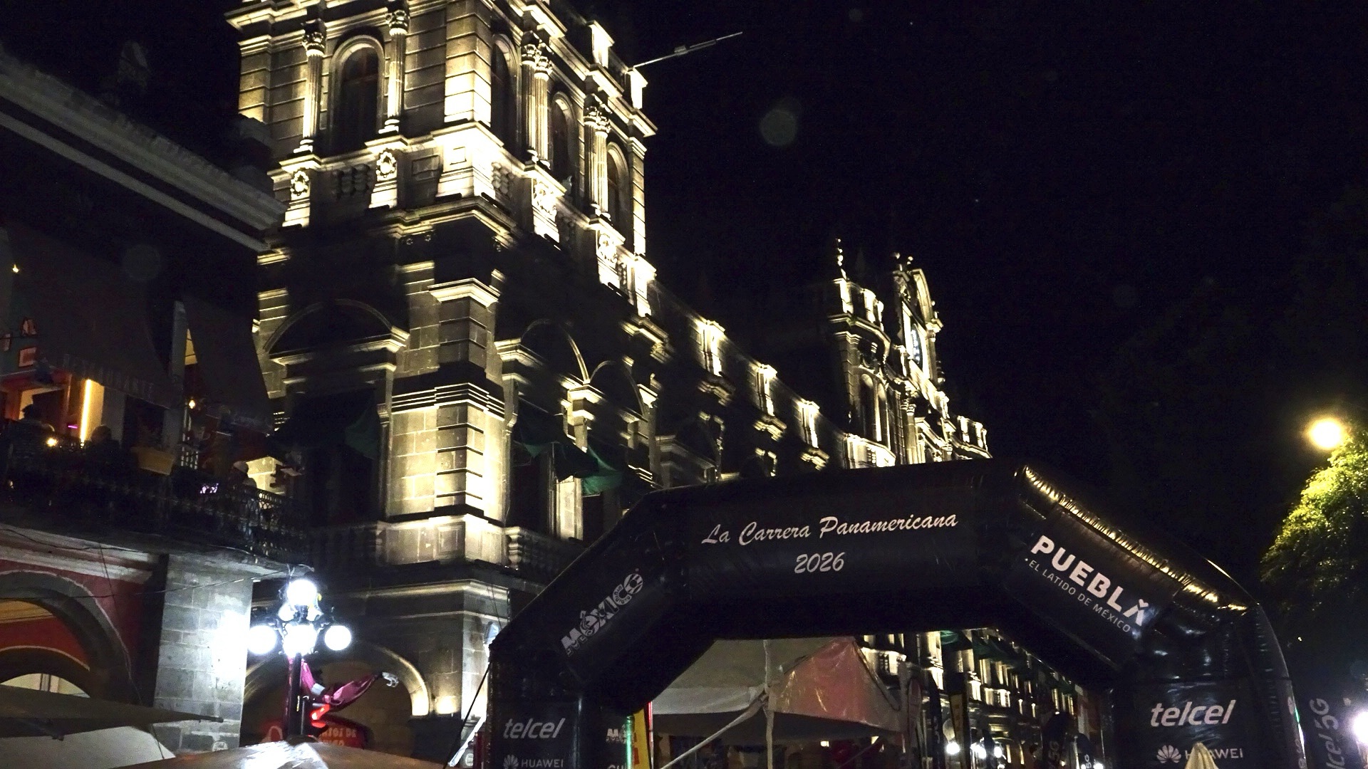 Arco de meta de La Carrera Panamericana 2026 de noche en el Zócalo de Puebla, con la Catedral iluminada al fondo